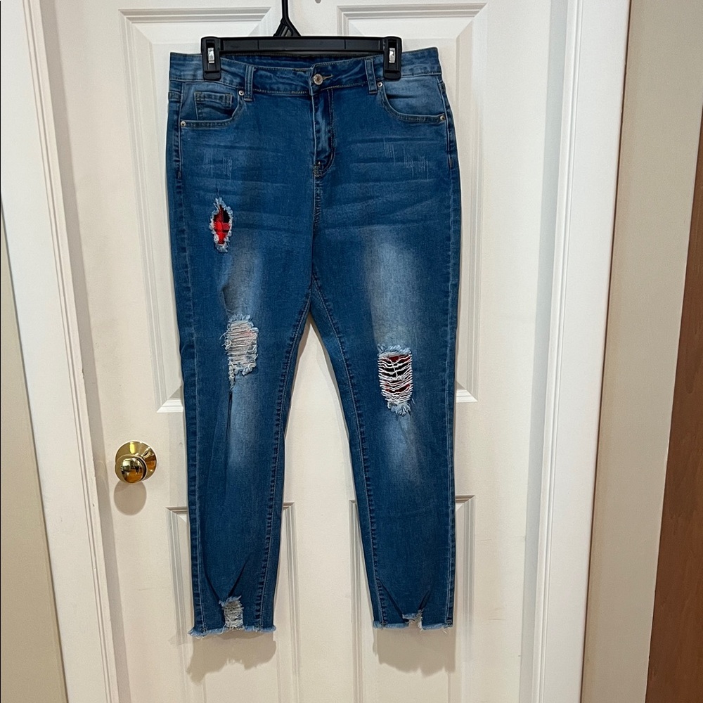 Blue, woman’s, distressed jeans, lined with red and black patches. Size large.